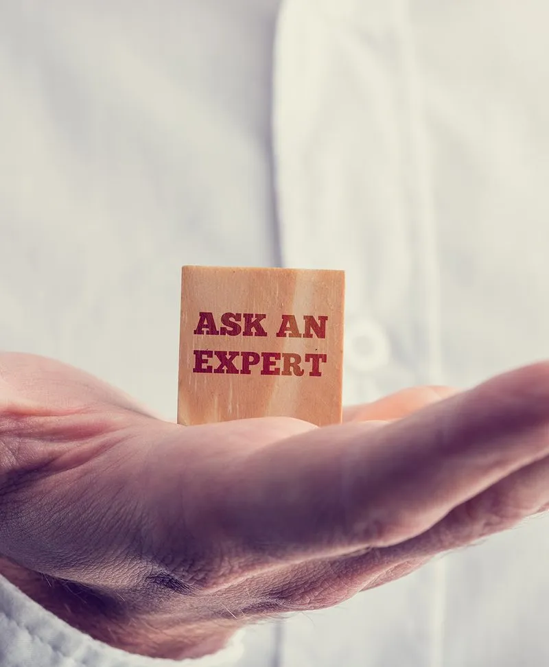 A hand holding a small block that reads “Ask an expert”