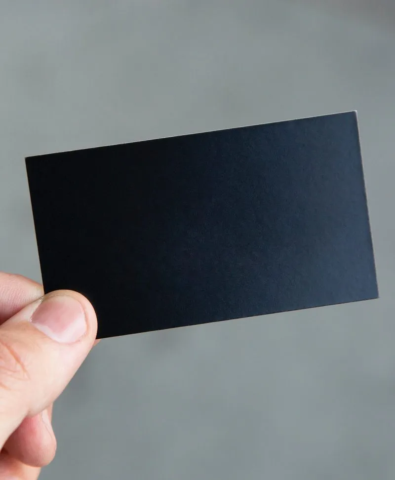 A hand holding a blank black card